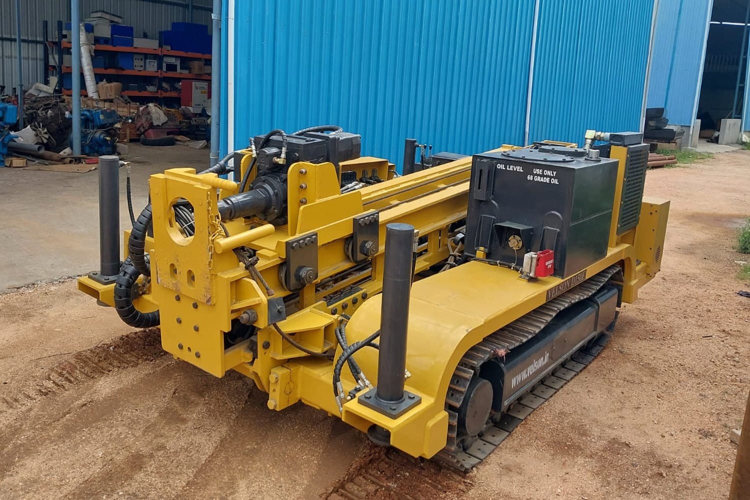Velson D150E crawler drill outside the plant shed - jack legs upright on the frame, hydraulic feed rails and oil tank across the deck